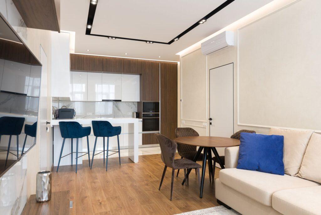 Bright modern Pune 2BHK living room with a modular TV unit, neutral laminate finishes, compact dining area and realistic apartment proportions; editorial, premium but practical.